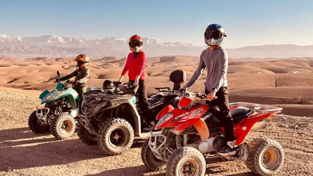 A quad bike rider on a track in the Agafay Desert with the Atlas Mountains in the distance