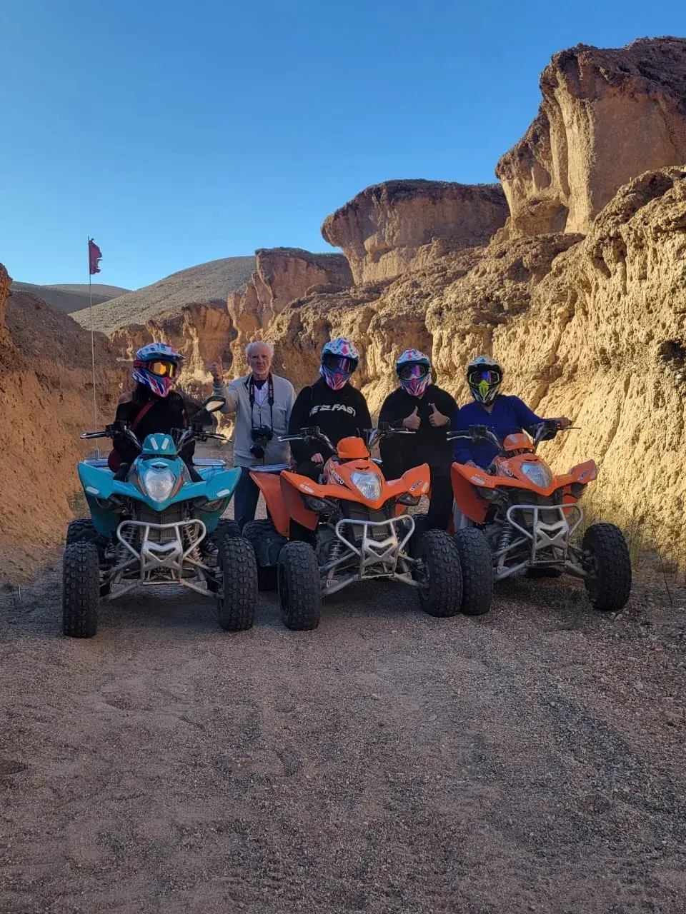 A group of quad bike riders in a rocky Agafay Desert canyon at golden hour